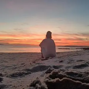 Ahogo emocional. Una persona sentada en la arena de la playa mirando al horizonte.