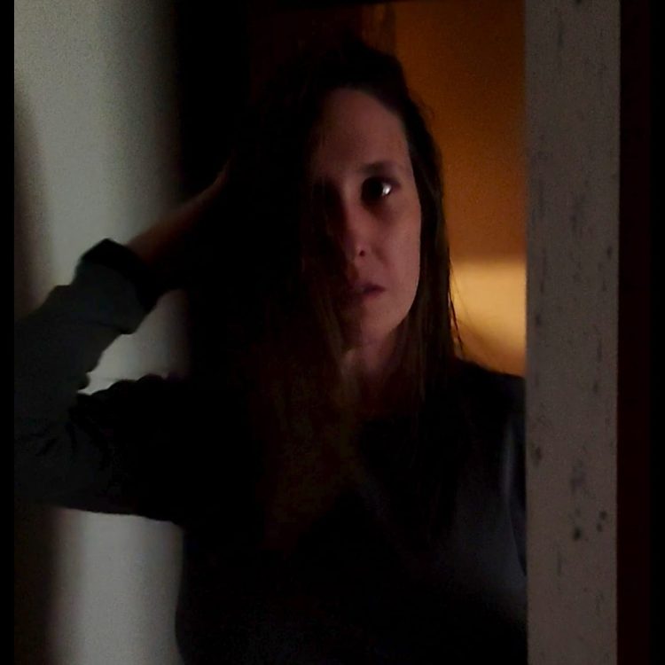 SandraAcuña en una imagen oscura frente a un espejo para representar la dualidad entre amarte o conformarte